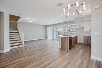 A living room and kitchen with a staircase and a kitchen island